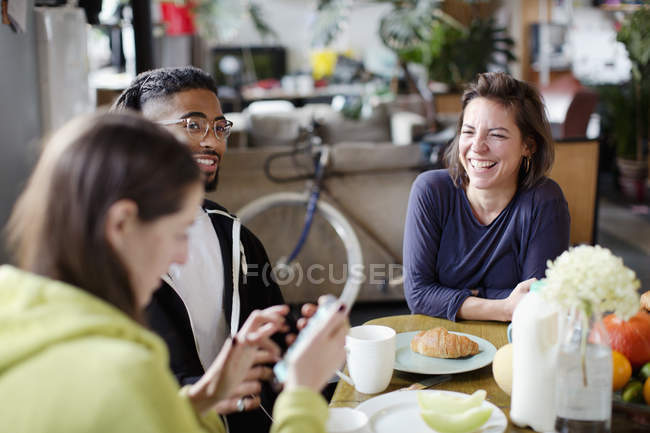 Jovens amigos companheiros de quarto adultos desfrutando de café da manhã na mesa de cozinha do apartamento — Fotografia de Stock