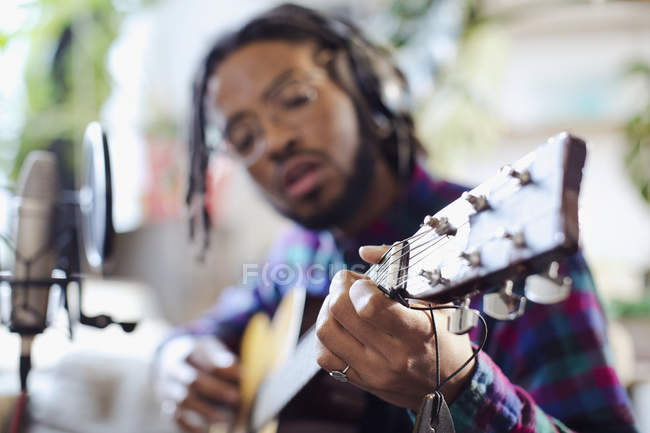 Junger männlicher Musiker nimmt Musik auf, spielt Gitarre am Mikrofon — Stockfoto