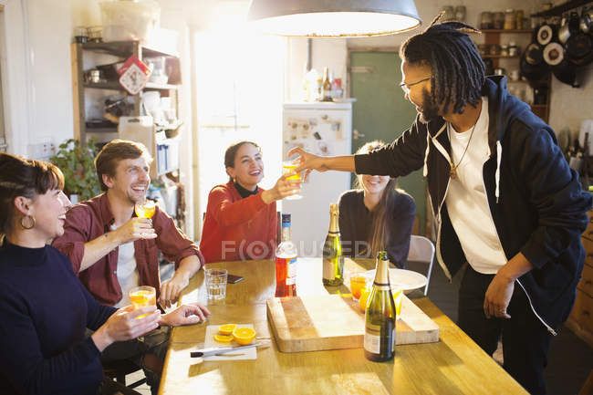 Молодих дорослих друзів, насолоджуючись коктейлями в квартирі кухонному столі — стокове фото