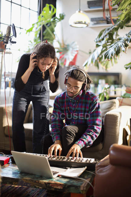 Young man and woman recording music, playing keyboard piano in apartment — Stock Photo