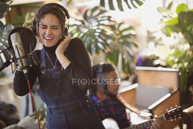 Молода жінка записує музику, співає на мікрофон — стокове фото