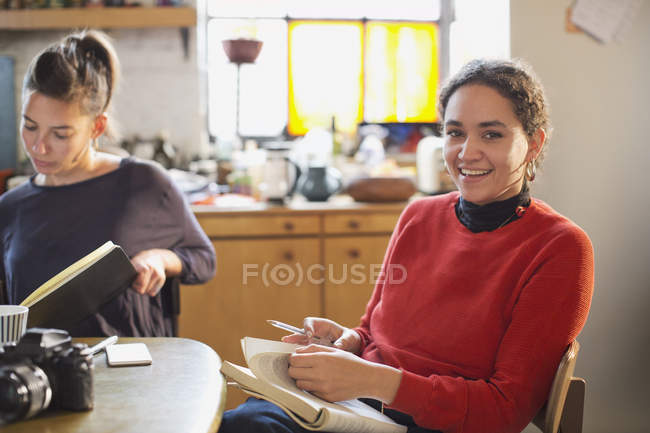 Retrato sorrindo estudante universitário feminino estudando na mesa da cozinha no apartamento — Fotografia de Stock