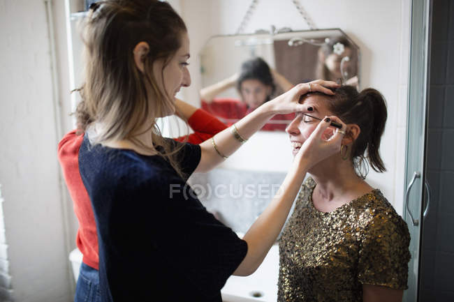 Young women getting ready, applying makeup in bathroom — Stock Photo