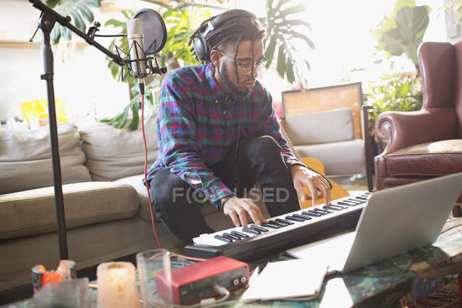 Молодий чоловік записує музику, грає на клавішному піаніно в квартирі — стокове фото