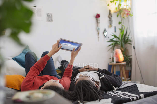 Jeune couple relaxant, en utilisant une tablette numérique sur le lit — Photo de stock