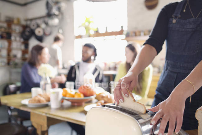 Woman using toaster, eating breakfast in apartment kitchen — Stock Photo