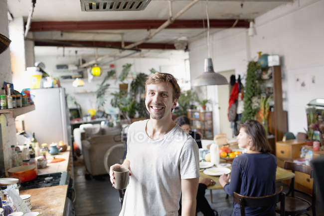 Portrait smiling man drinking coffee in apartment kitchen — Stock Photo