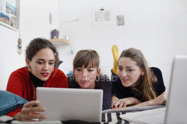 Jeunes femmes amis partageant tablette numérique sur le lit — Photo de stock