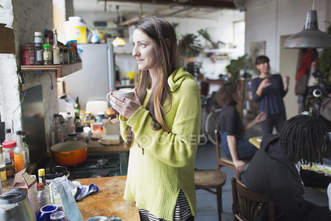Задумчивая молодая женщина пьет кофе на кухне — стоковое фото