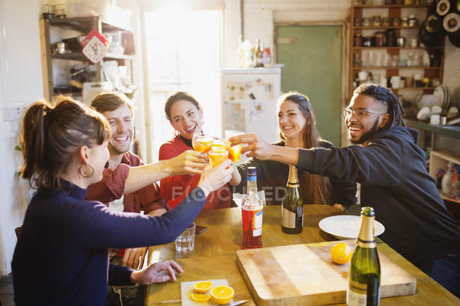 Heureux jeunes amis adultes griller des cocktails à la table de cuisine appartement — Photo de stock