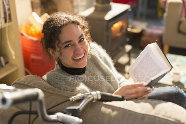 Porträt lächelnde, glückliche junge Frau liest Buch im Sessel — Stockfoto