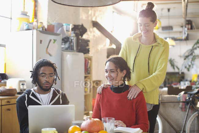 Jóvenes estudiantes universitarios que estudian en la mesa de la cocina en el apartamento - foto de stock
