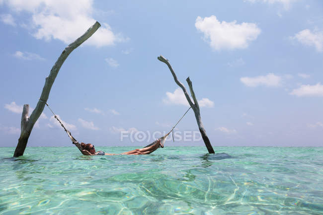Woman laying in hammock over tranquil ocean, Maldives, Indian Ocean — Stock Photo