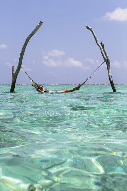 Jovem mulher deitada na rede sobre tranquilo oceano azul, Maldivas, Oceano Índico — Fotografia de Stock