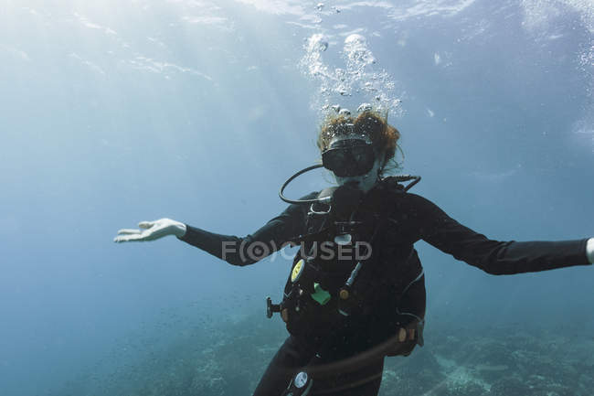 Portrait young woman scuba diving underwater with arms outstretched — Stock Photo