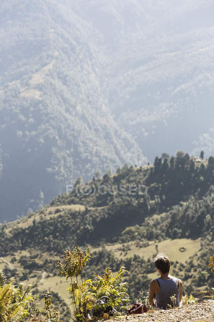 Senderista descansando, disfrutando de soleadas colinas verdes vista, Supi Bageshwar, Uttarakhand, Indio Himalaya Foothills - foto de stock