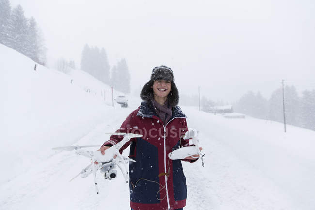 Portrait smiling teenage boy with drone in snowy landscape — Stock Photo