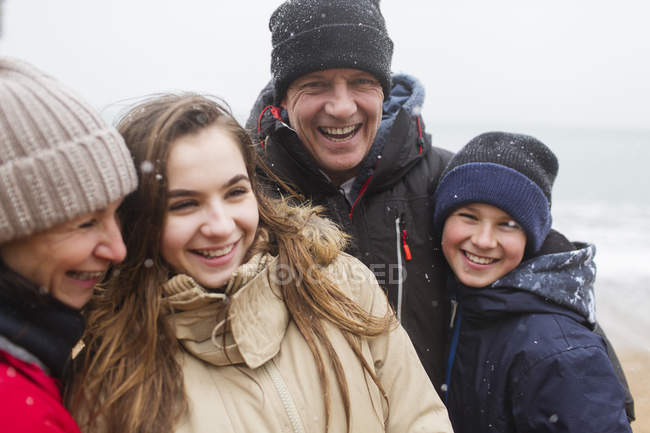 Сніг падає над щасливою сім'єю в теплому одязі — стокове фото