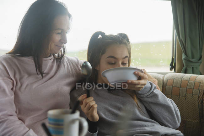Mother watching daughter finishing cereal in motor home — Stock Photo