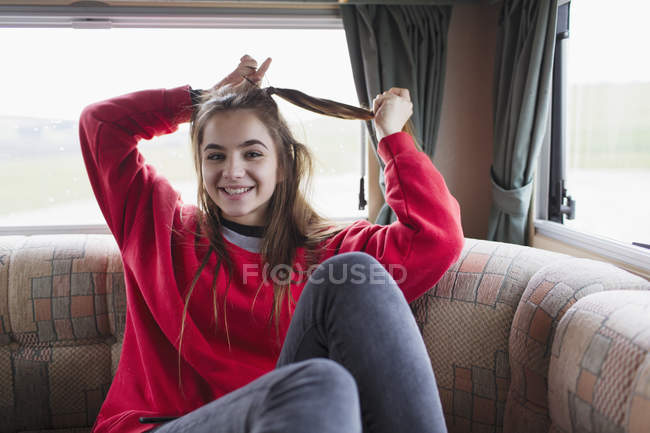 Portrait smiling teenage girl fixing hair in motor home — Stock Photo