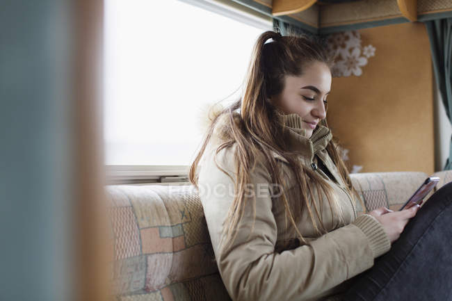 Menina adolescente mensagens de texto com telefone inteligente em casa motor — Fotografia de Stock