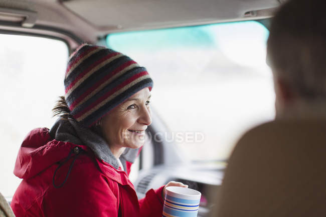 Donna sorridente che beve caffè nel camper — Foto stock