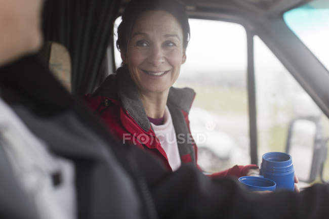 Donna sorridente che beve caffè nel camper — Foto stock