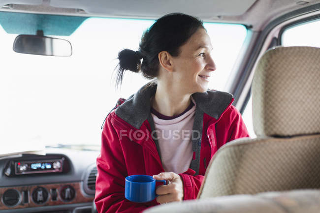 Улыбающаяся женщина пьет кофе в доме на колёсах — стоковое фото