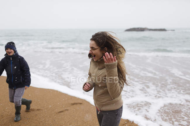 Грайлива дівчина-підліток на засніженому зимовому пляжі — стокове фото