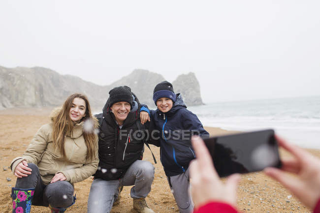 Glückliche Familie posiert für Foto am verschneiten Winterstrand — Stockfoto
