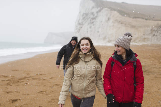 Affectionate mother and daughter walking on snowy winter beach — Stock Photo