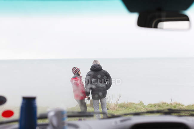 Casal em pé fora do motor home no penhasco com vista para o oceano — Fotografia de Stock