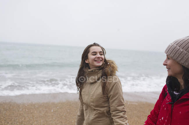Мати і дочка в теплому одязі, що йде на пляжі зимового океану — стокове фото