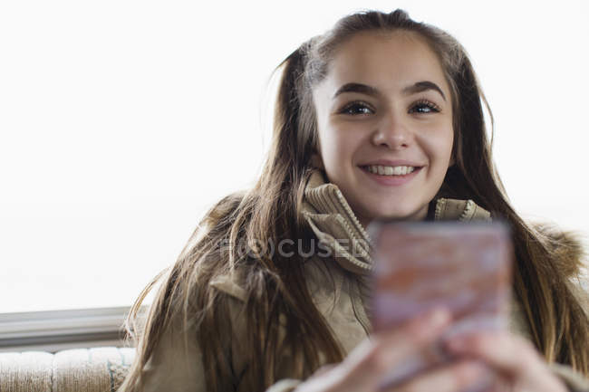 Улыбающаяся портрет, уверенная в себе девочка-подросток, которая пишет смс со смартфона — стоковое фото
