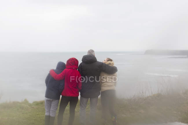 Семья в теплой одежде наслаждается видом на океан — стоковое фото