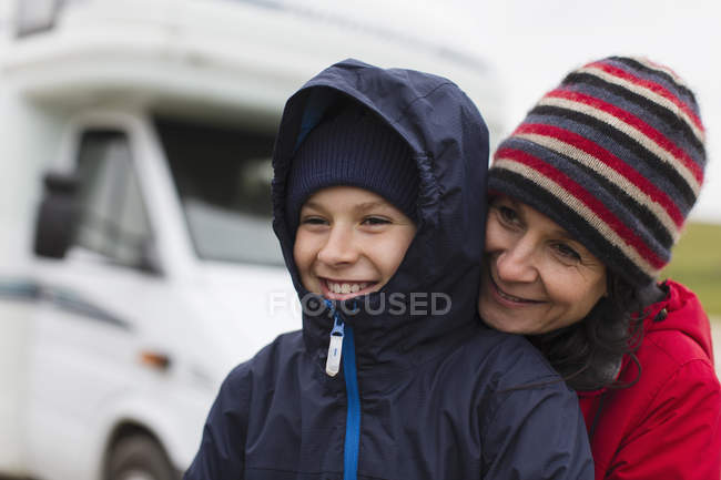 Прихильна мати і син в теплому одязі обіймаються поза мотором будинку — стокове фото