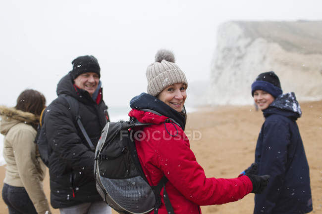 Портрет усміхненої сім'ї в теплому одязі на засніженому зимовому пляжі — стокове фото