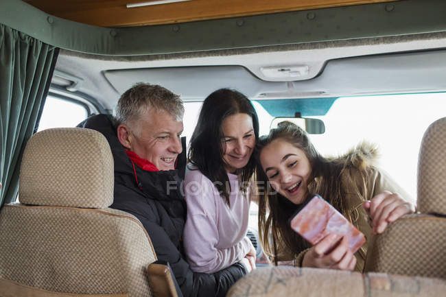 Familia feliz con teléfono inteligente tomando selfie en autocaravana - foto de stock