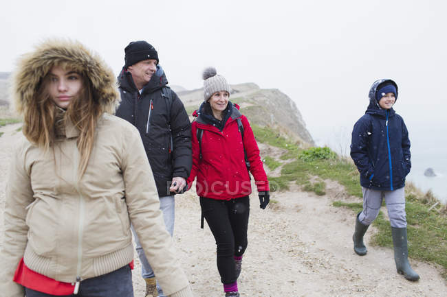 Familia en ropa de abrigo caminando por el camino nevado del acantilado de invierno - foto de stock