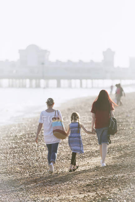 Пару лесбіянок і дочка, тримаючись за руки на сонячному пляжі — стокове фото