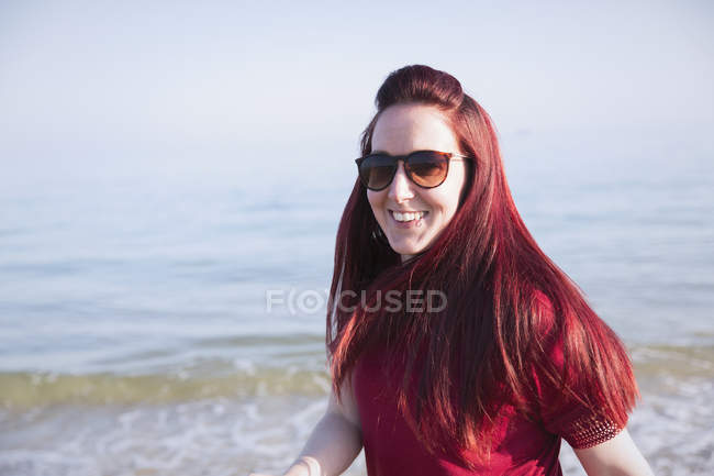 Retrato sonriente, mujer confiada en la soleada playa del océano - foto de stock