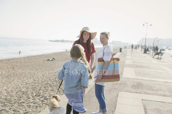 Lesbian couple with daughter and dog on sunny beach boardwalk — Stock Photo