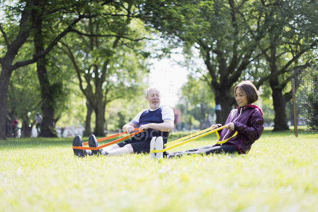 Активные упражнения для пожилых пар, использование полос сопротивления в парке — стоковое фото
