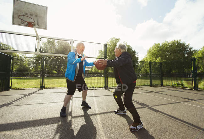 Homens idosos ativos amigos jogando basquete no parque ensolarado — Fotografia de Stock