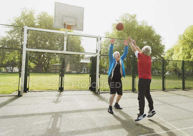 Homens idosos ativos amigos jogando basquete no parque ensolarado — Fotografia de Stock