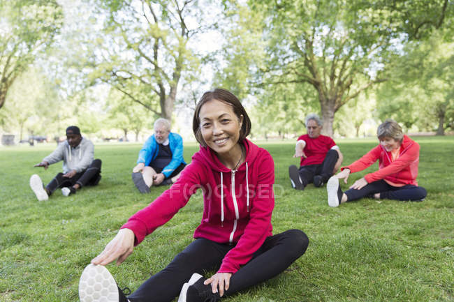 Portrait smiling, confident active senior woman stretching in park — Stock Photo