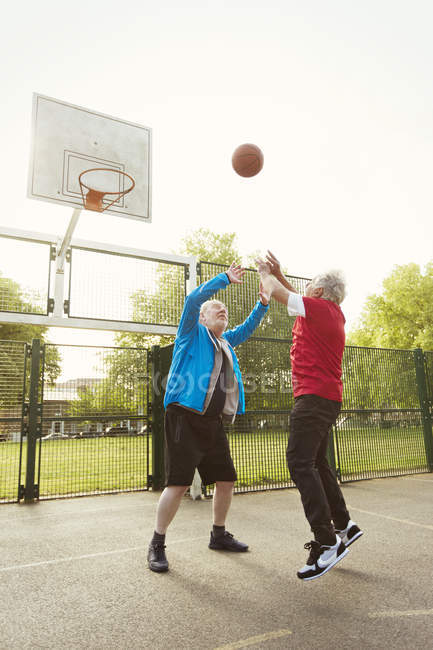 Hombres mayores activos amigos jugando baloncesto en el parque - foto de stock