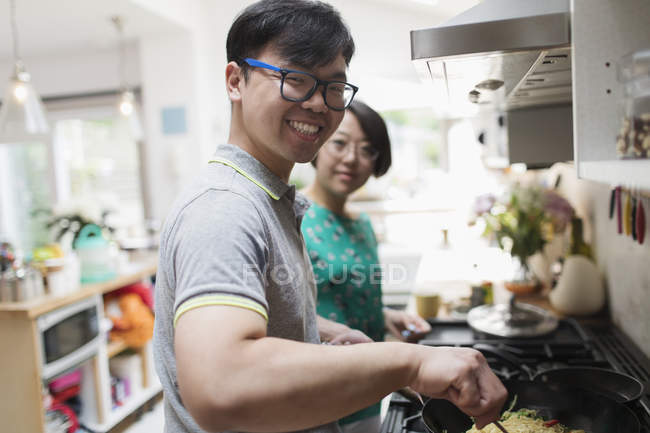 Portrait smiling couple cooking at stove in kitchen — Stock Photo