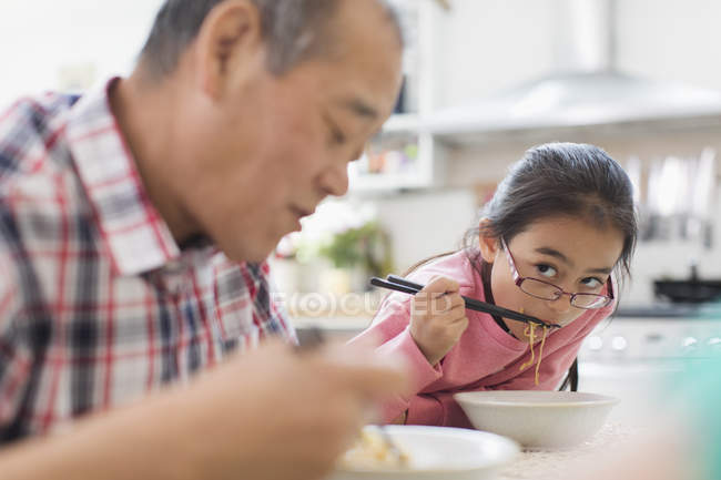 Дідусь і онука їдять локшину на кухні — стокове фото