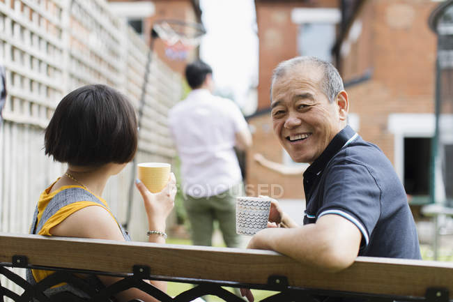 Portrait happy senior man drinking tea with family in back yard — Stock Photo